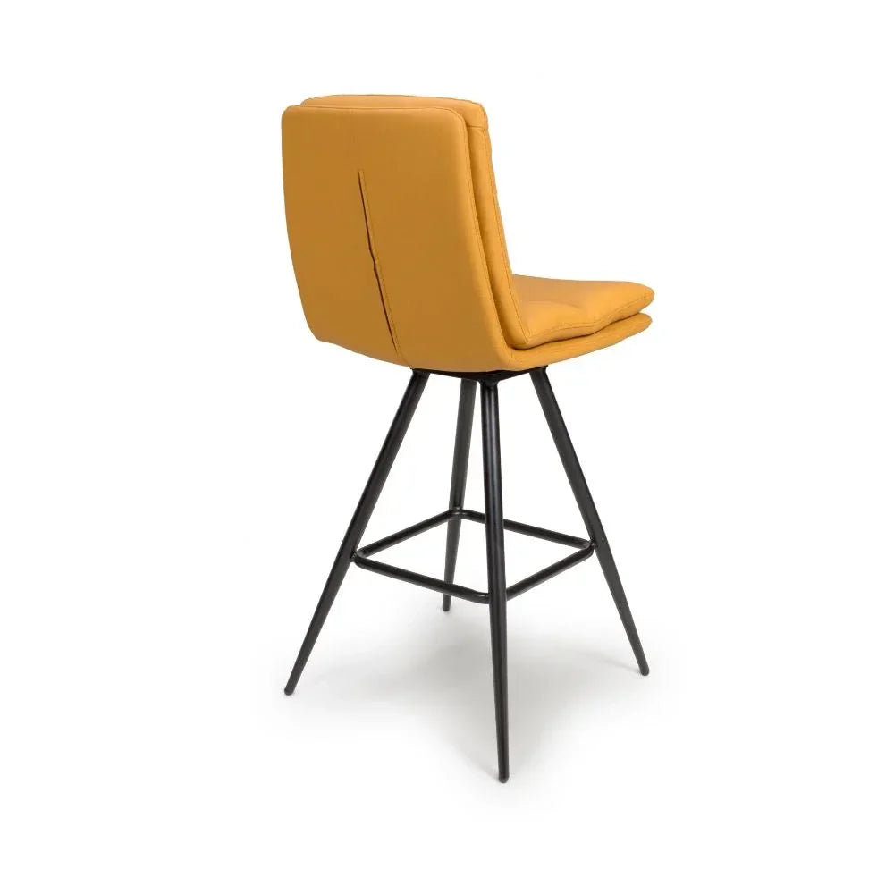 Mustard yellow bar stool with padded backrest and black metal legs, rear angle view