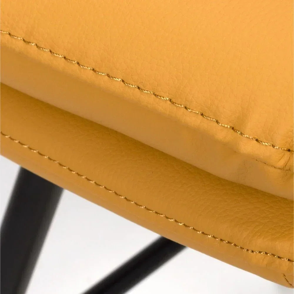 Closeup of yellow faux leather dining chair seat with black metal leg visible