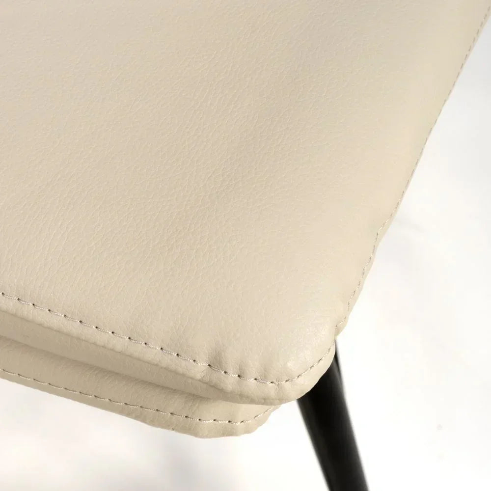 Closeup of beige faux leather dining chair seat with black metal leg