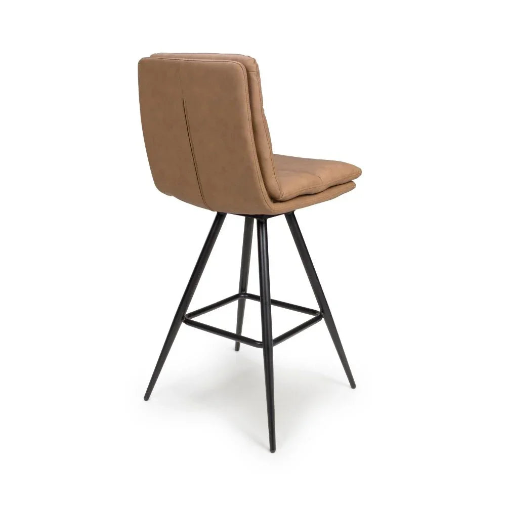 Tan faux leather bar stool with black metal legs, angled rear view