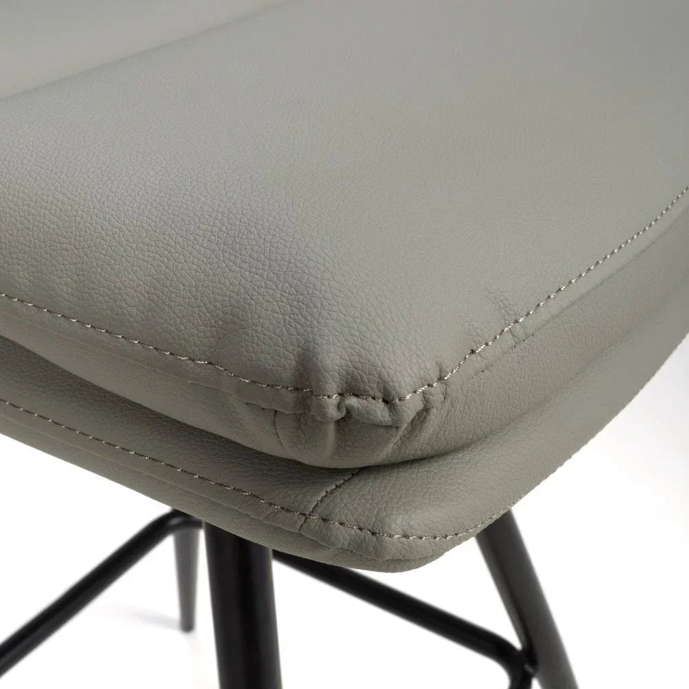 Close-up of grey faux leather bar stool seat with black metal legs and visible stitching detail