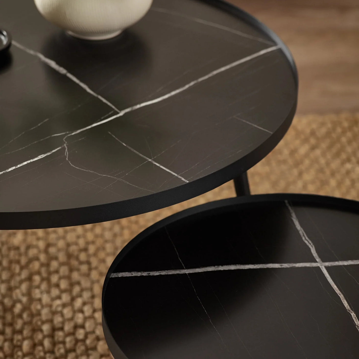 Black marble effect nesting coffee tables with white veining on woven rug