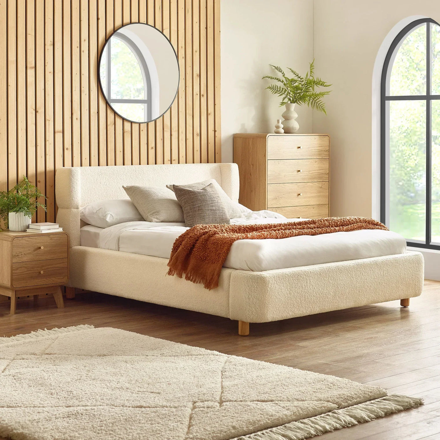 cream upholstered bed with wooden legs, matching bedside table and chest in modern bedroom