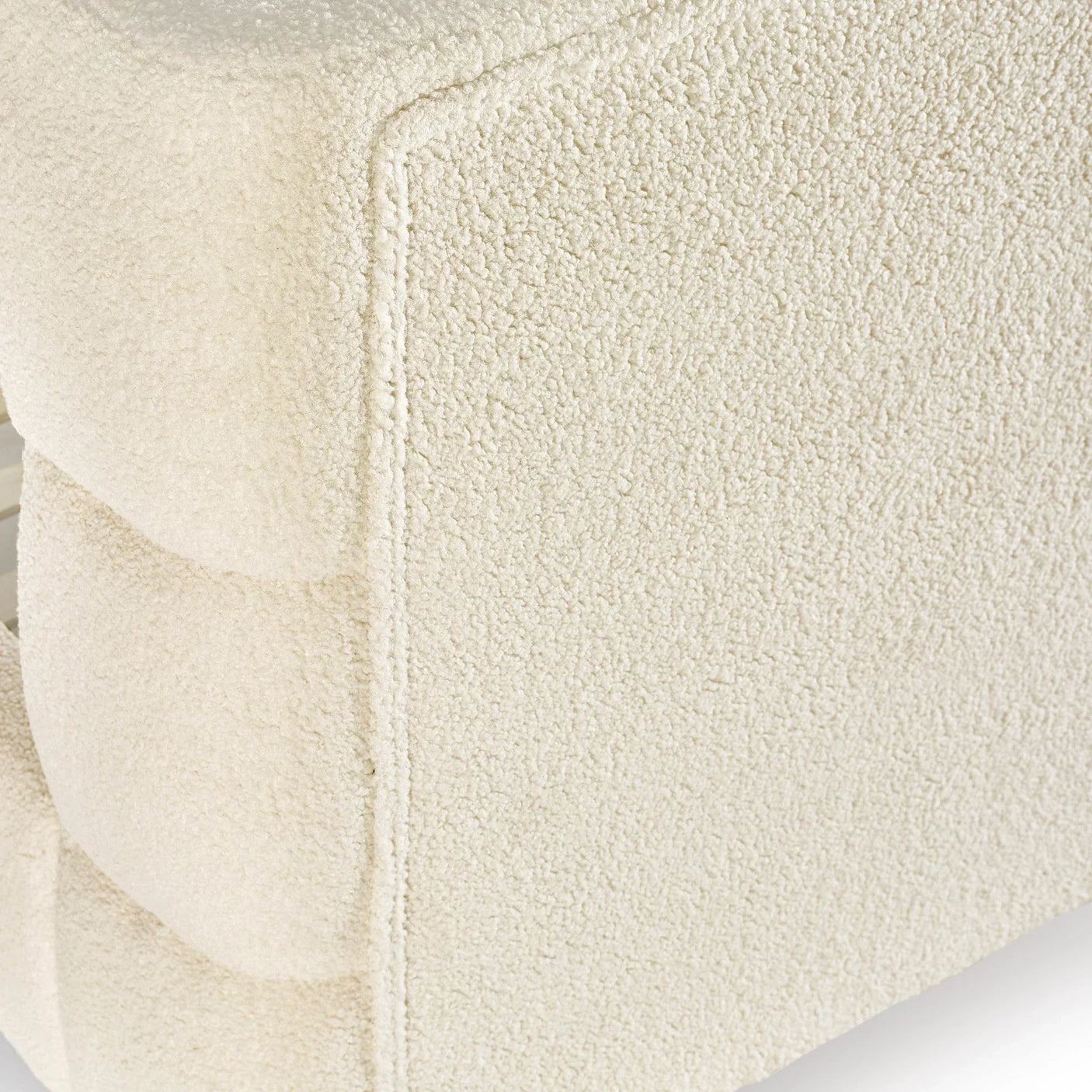 Close-up of cream boucle sofa armrest with textured upholstery and seam detail