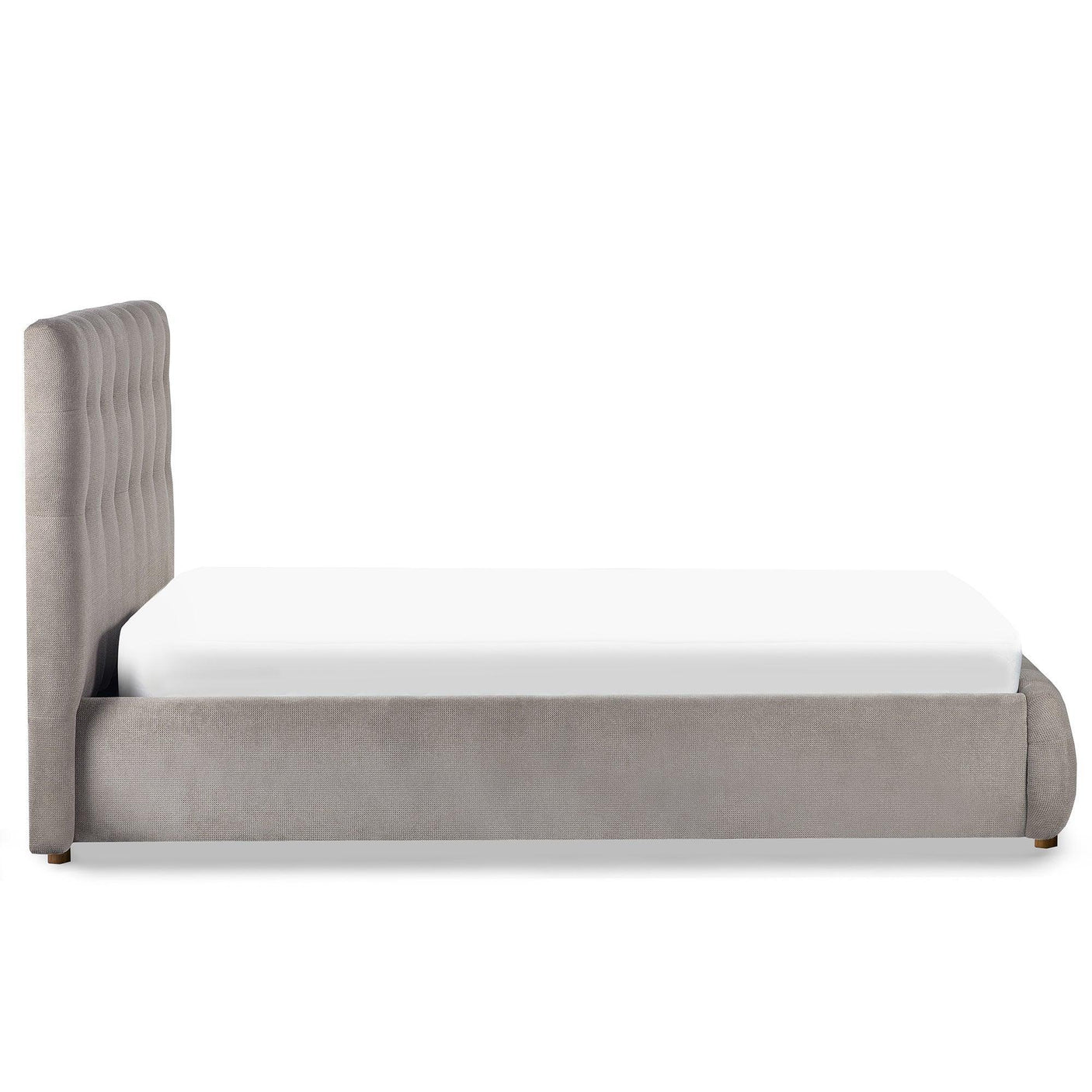 Grey upholstered bed frame with tall tufted headboard, side view on white background