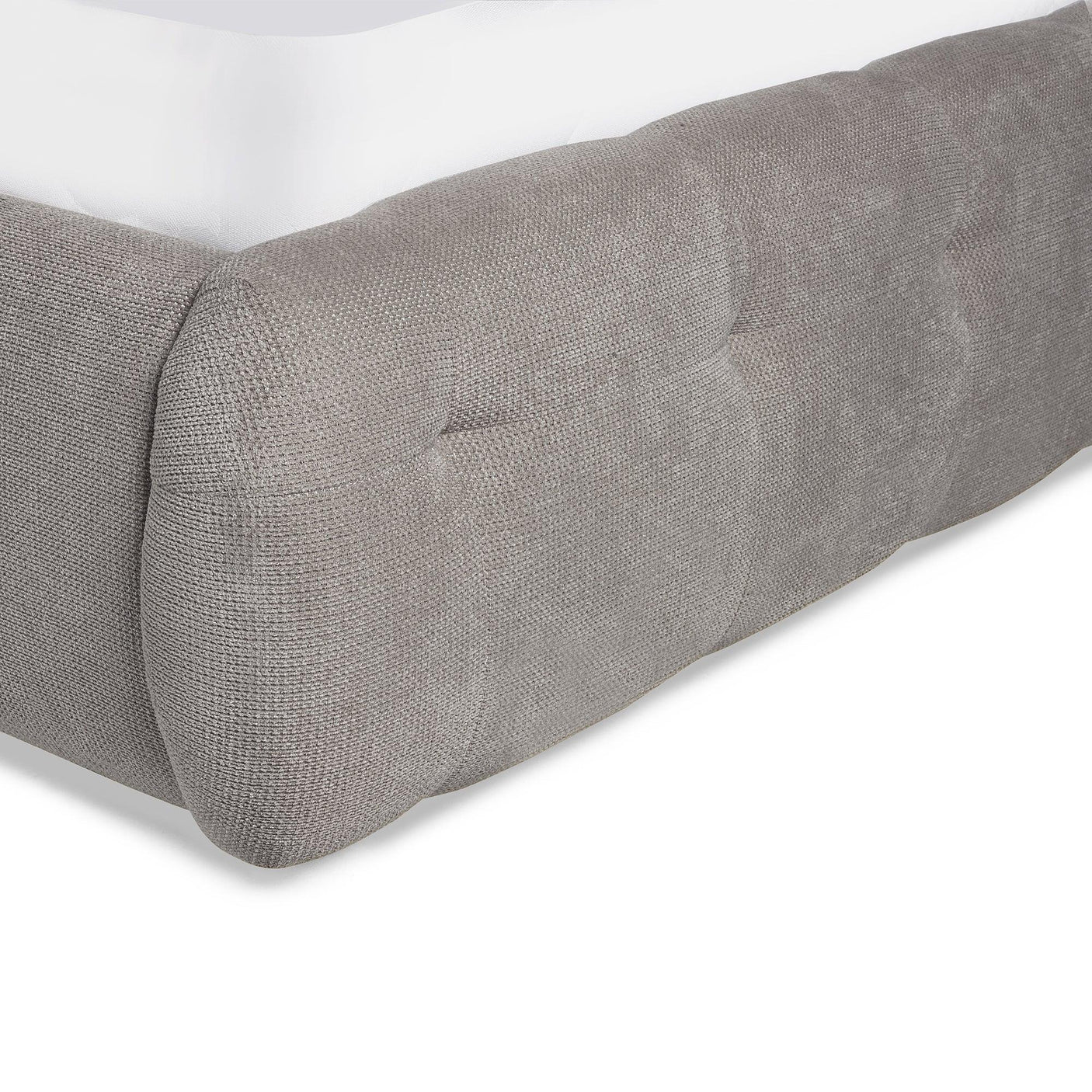 Closeup of grey fabric bed frame with tufted detail and low corner design