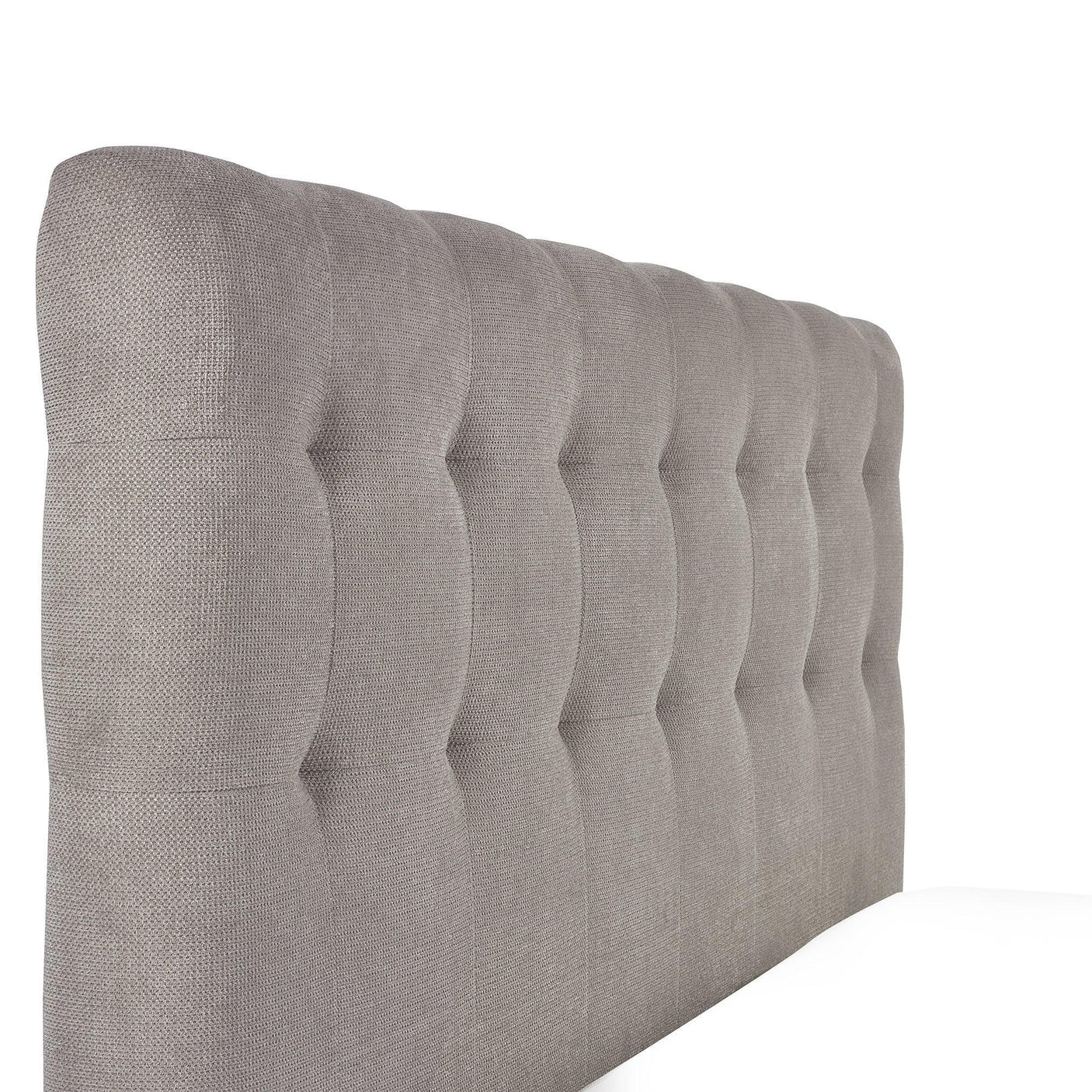 Close-up of grey fabric upholstered bed headboard with vertical tufted detail