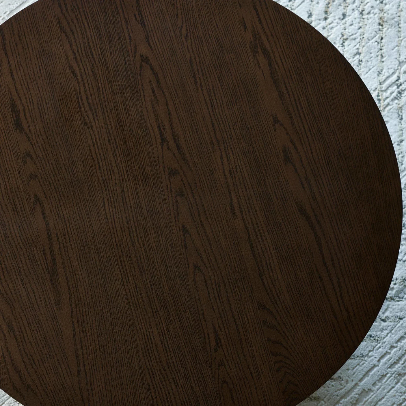 Round dark wood dining table top with visible grain on light textured rug