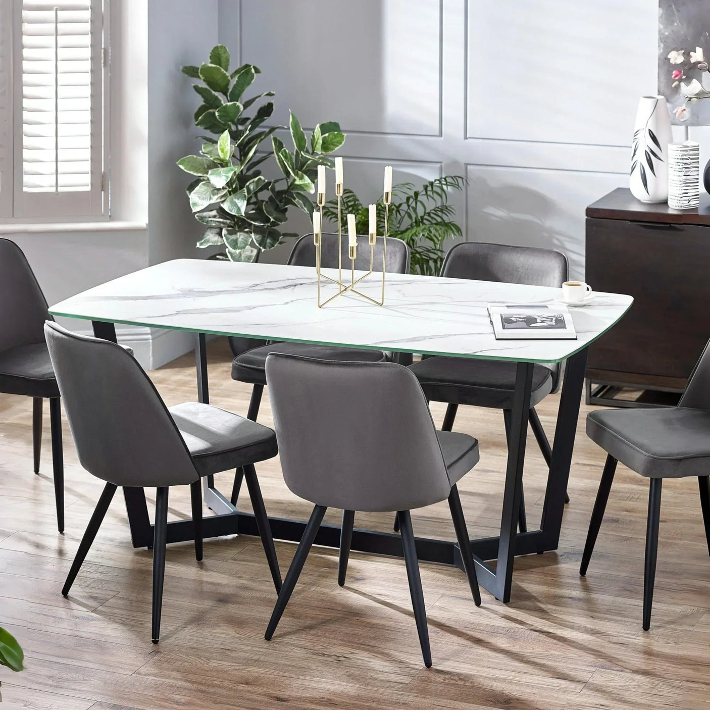 Marble dining table with six grey upholstered chairs in modern dining room setting