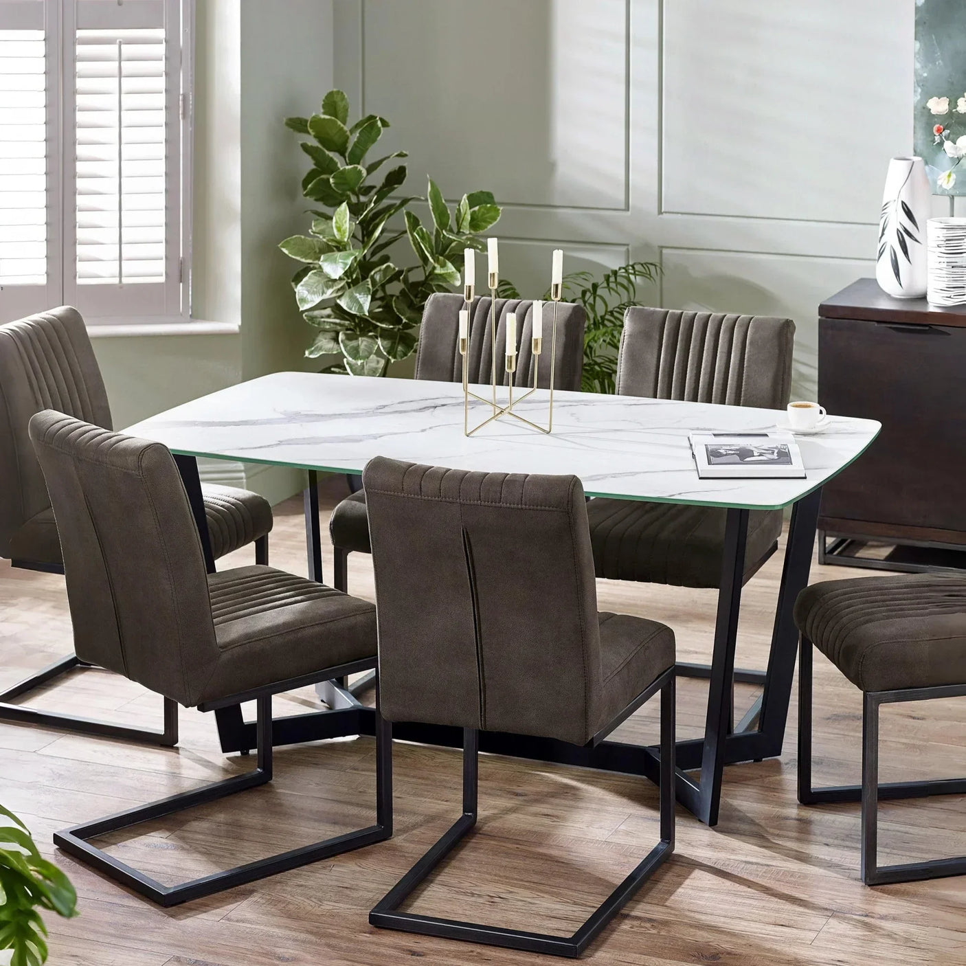 Modern marble dining table with six grey fabric chairs and metal legs in contemporary room