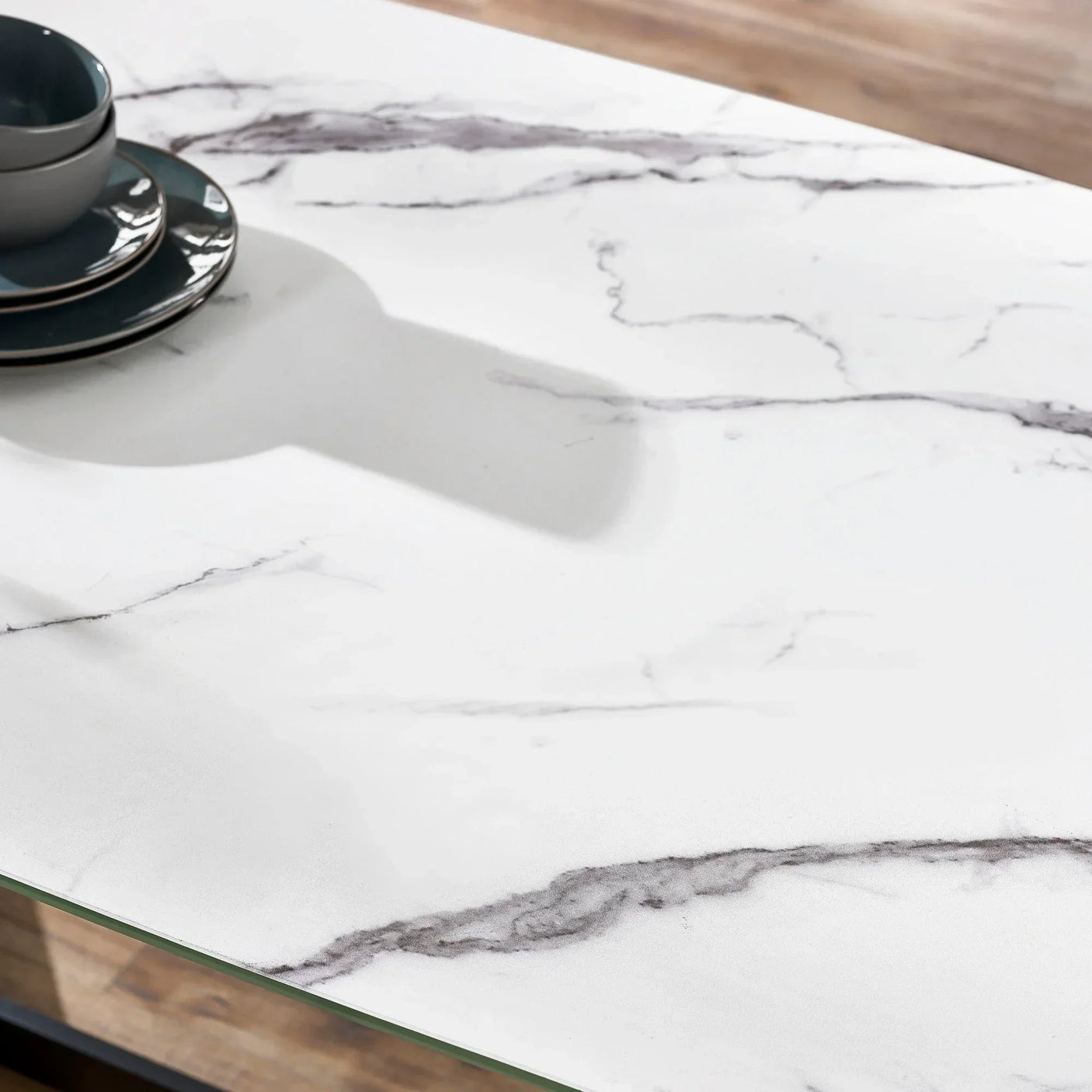 White marble dining table surface with grey veining and dark crockery placed on top