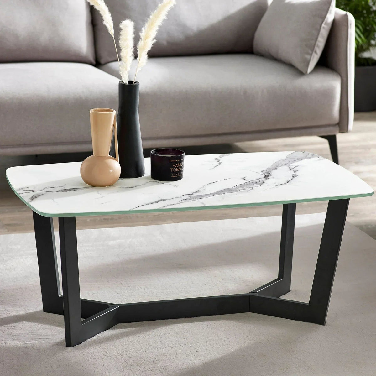 White marble-effect coffee table in a living room with vases and a candle on top