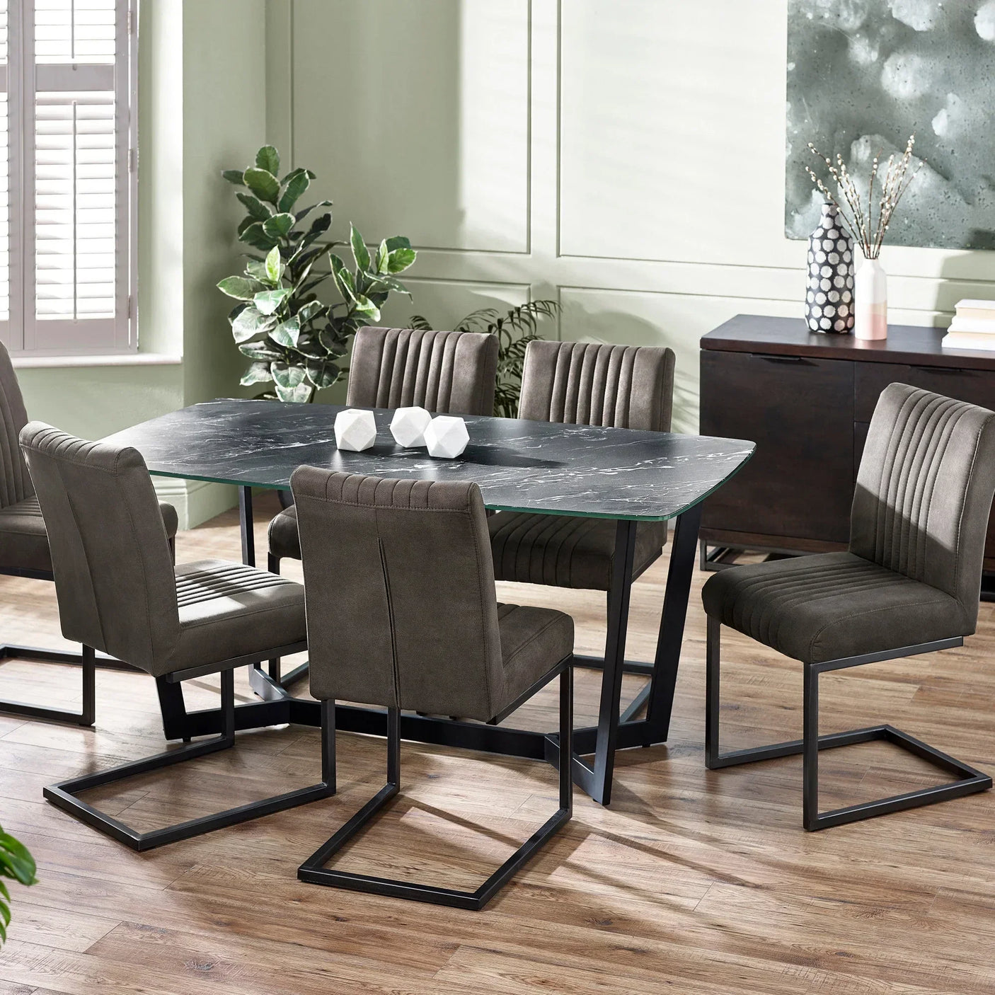 Modern marble dining table with six grey velvet chairs on wooden floor in bright dining room