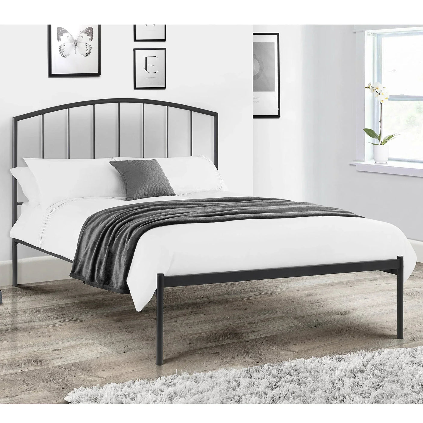 Black metal bed frame with vertical slats, white bedding, and grey throw in modern bedroom