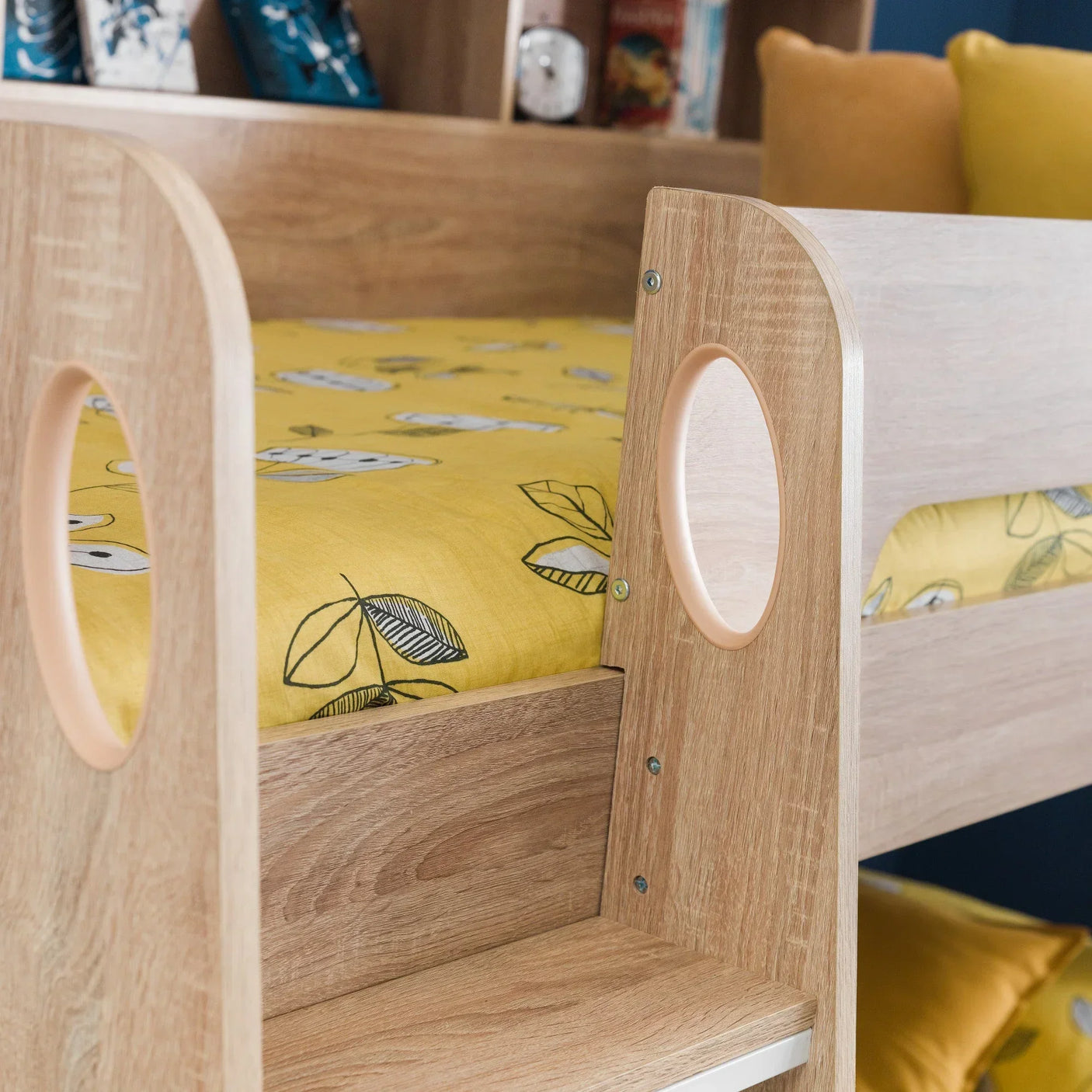 Oak finish bunk bed frame with yellow bedding and circular cutout ladder detail