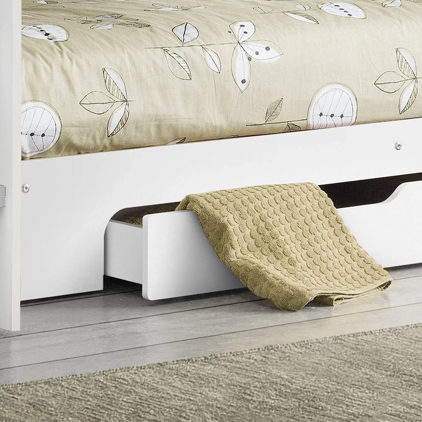 White bed frame with underbed storage drawer and beige textured blanket on wooden floor