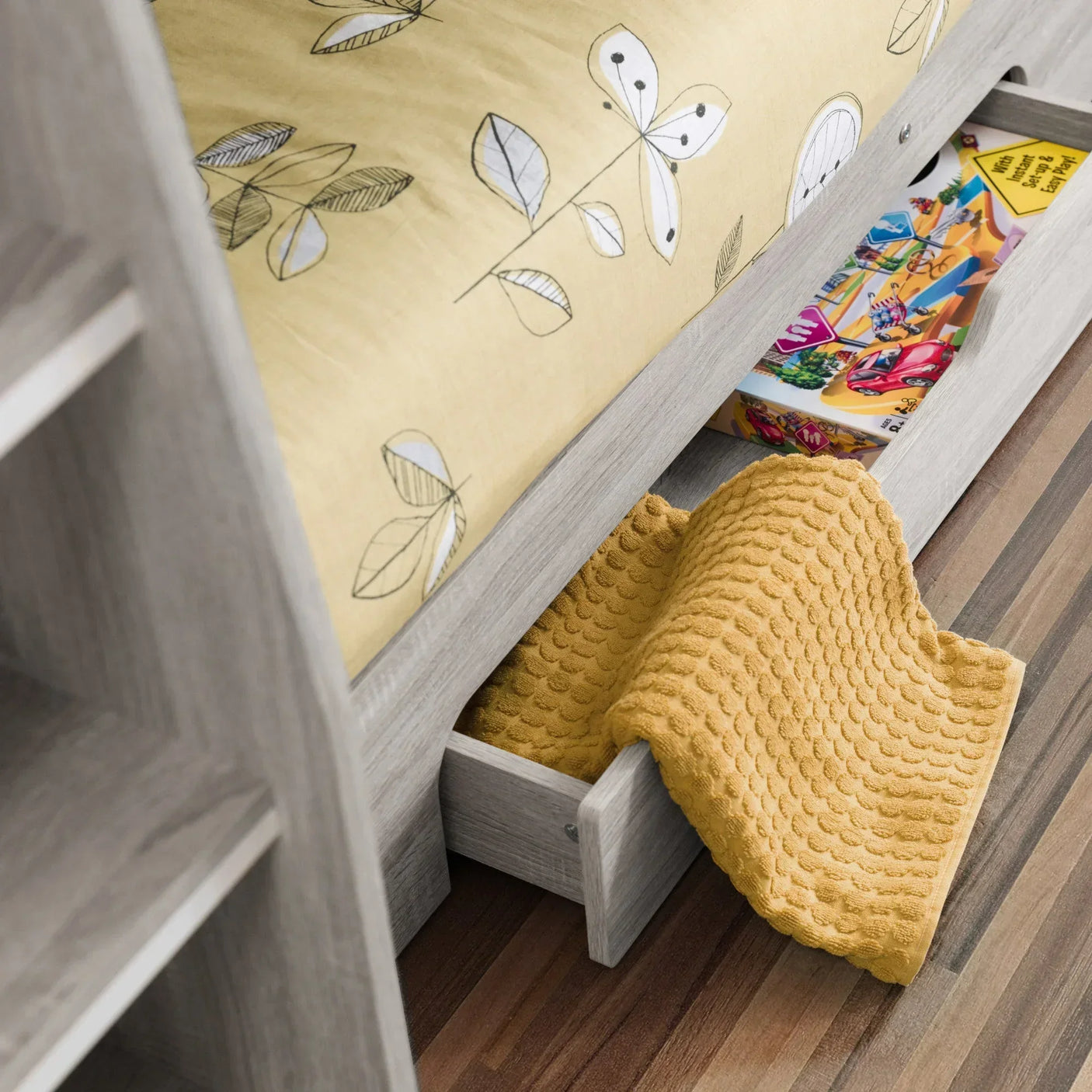 Wooden bed frame with underbed storage drawer partially open, showing yellow blanket and toys