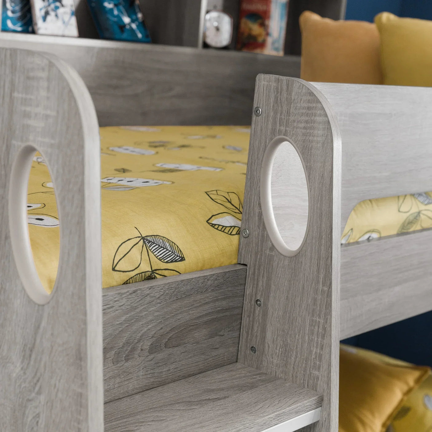 Light wood bunk bed frame with yellow leaf print bedding and circular cutout detail
