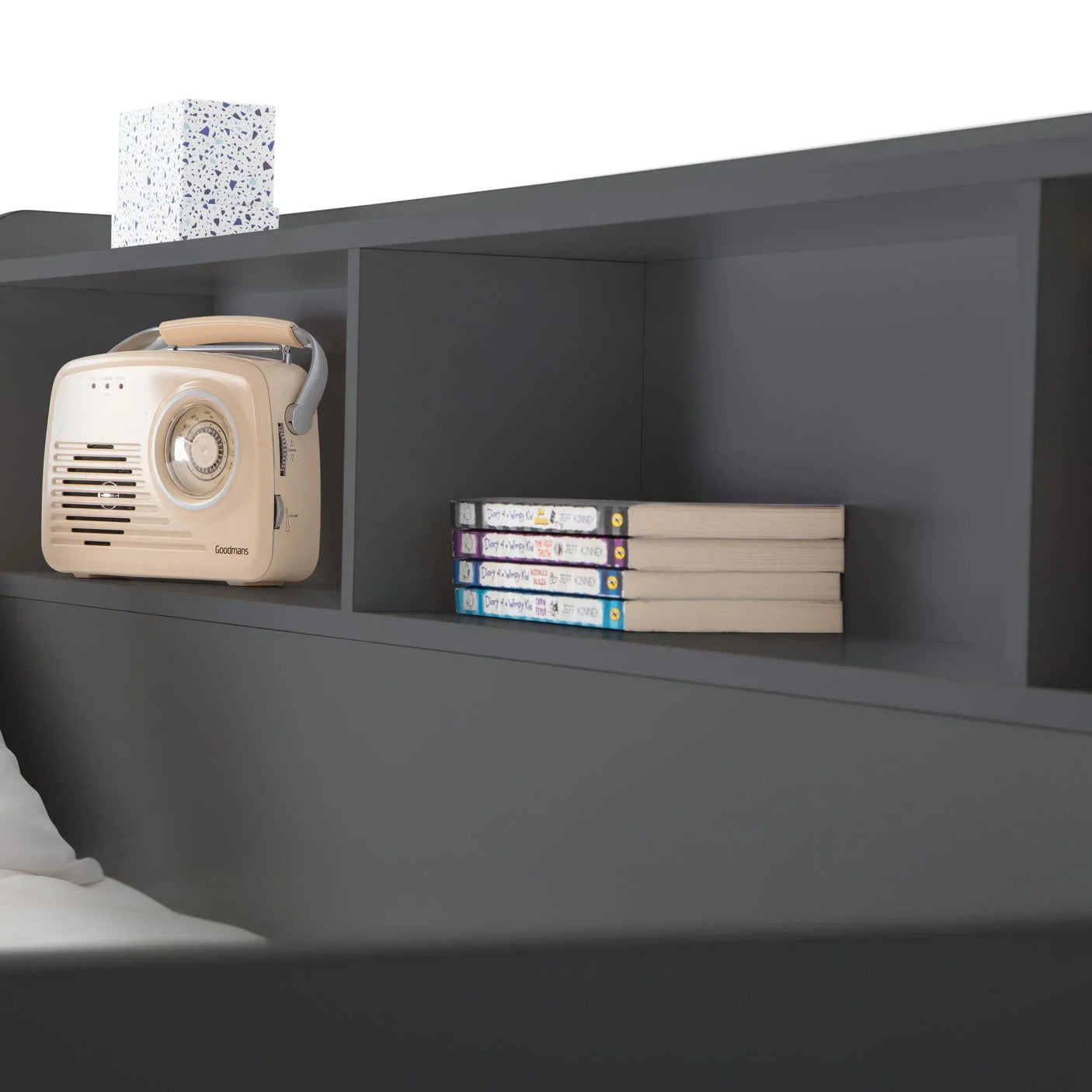 Black wooden headboard shelf with books, radio, and decorative box