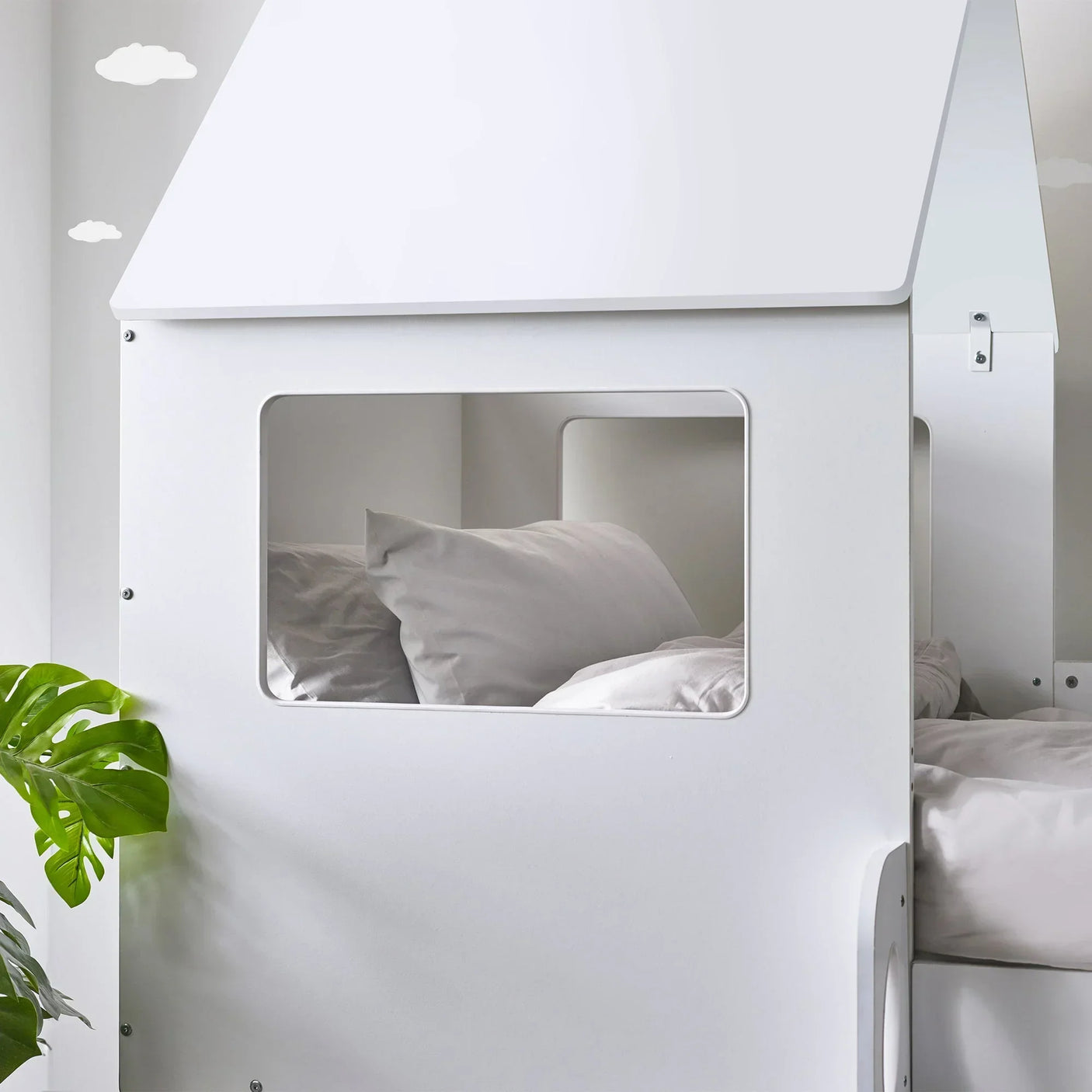 White midsleeper bed with house-style frame, window opening, and pillows in a modern room