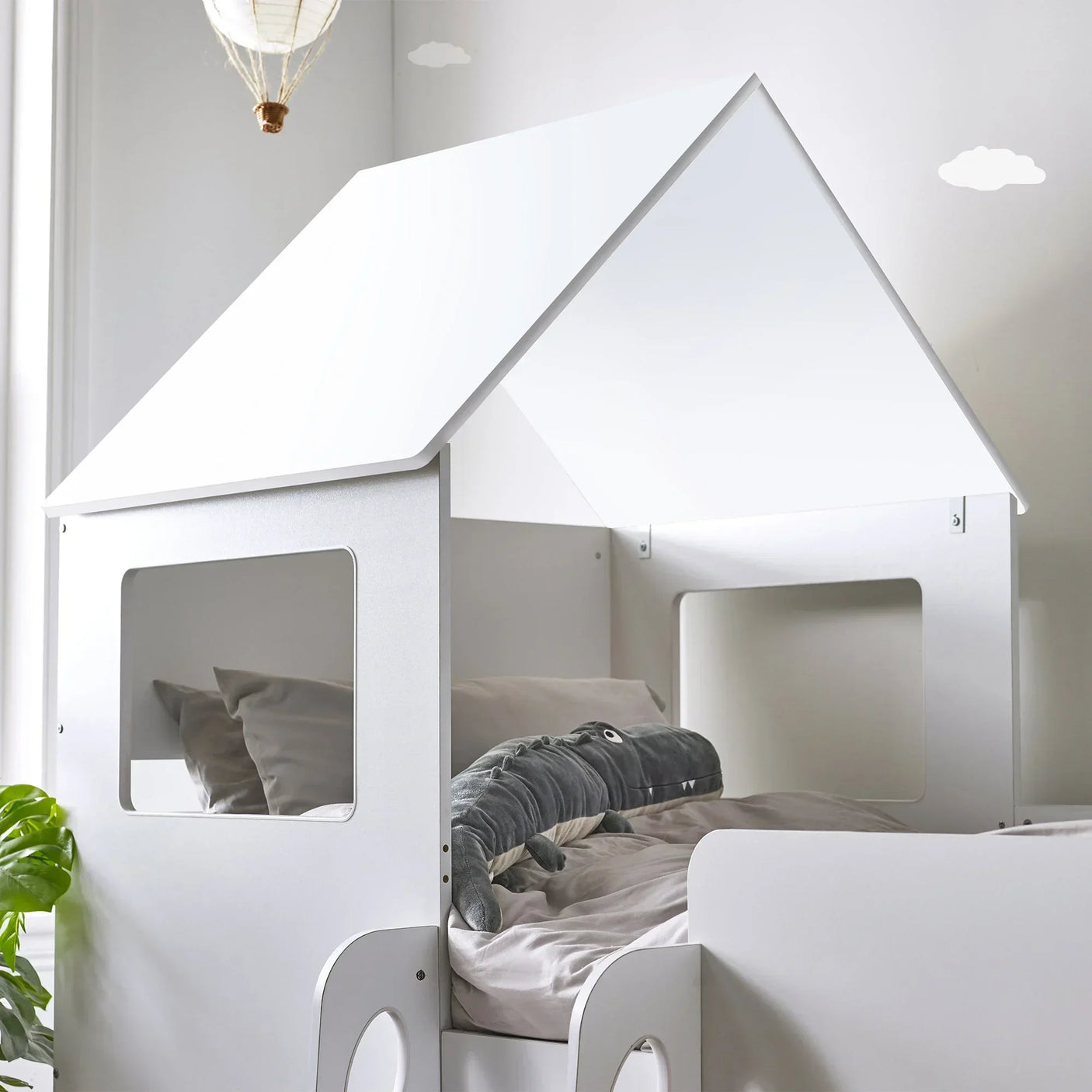 White midsleeper house bed with window cutouts and soft bedding in kids’ room