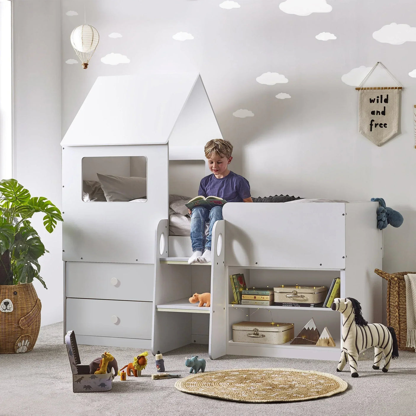 White midsleeper cabin bed with stairs, storage drawers, and a child reading on top