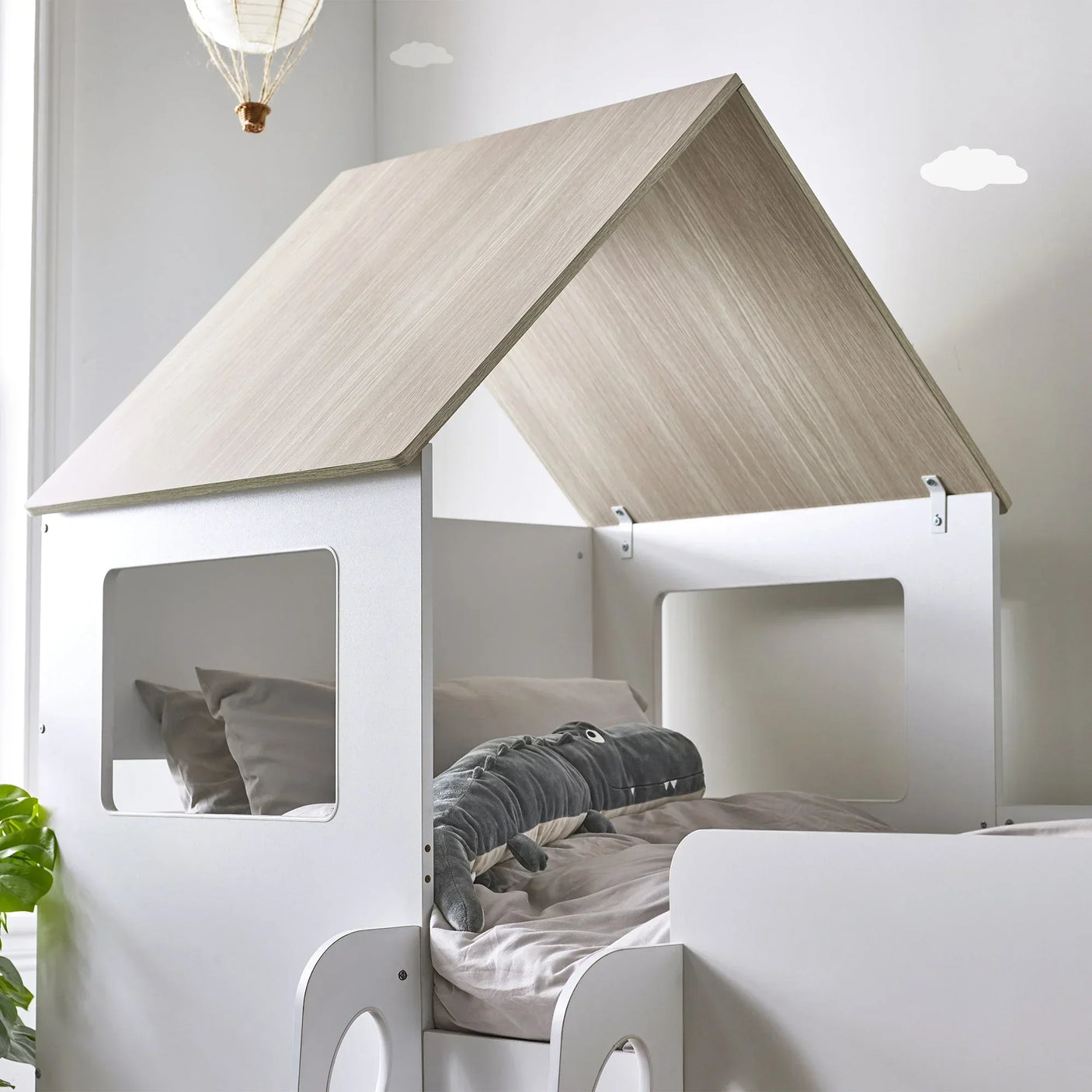 Pale wood mid sleeper bed with white frame and house-shaped roof in children's room