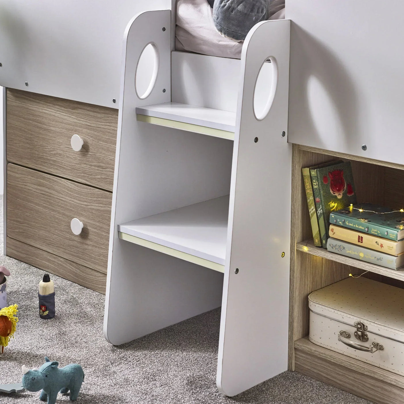 Orpheus midsleeper bed with pale wood drawers, white ladder steps, and bookshelf detail
