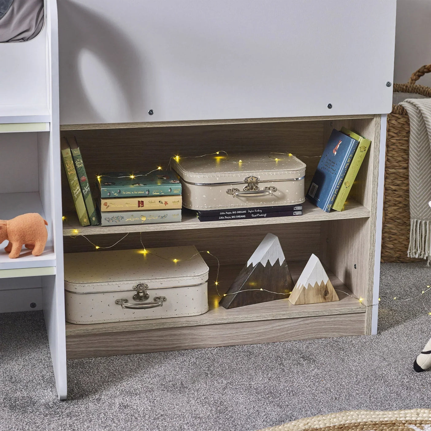 Orpheus midsleeper bed shelving in pale wood with fairy lights, books, and storage boxes