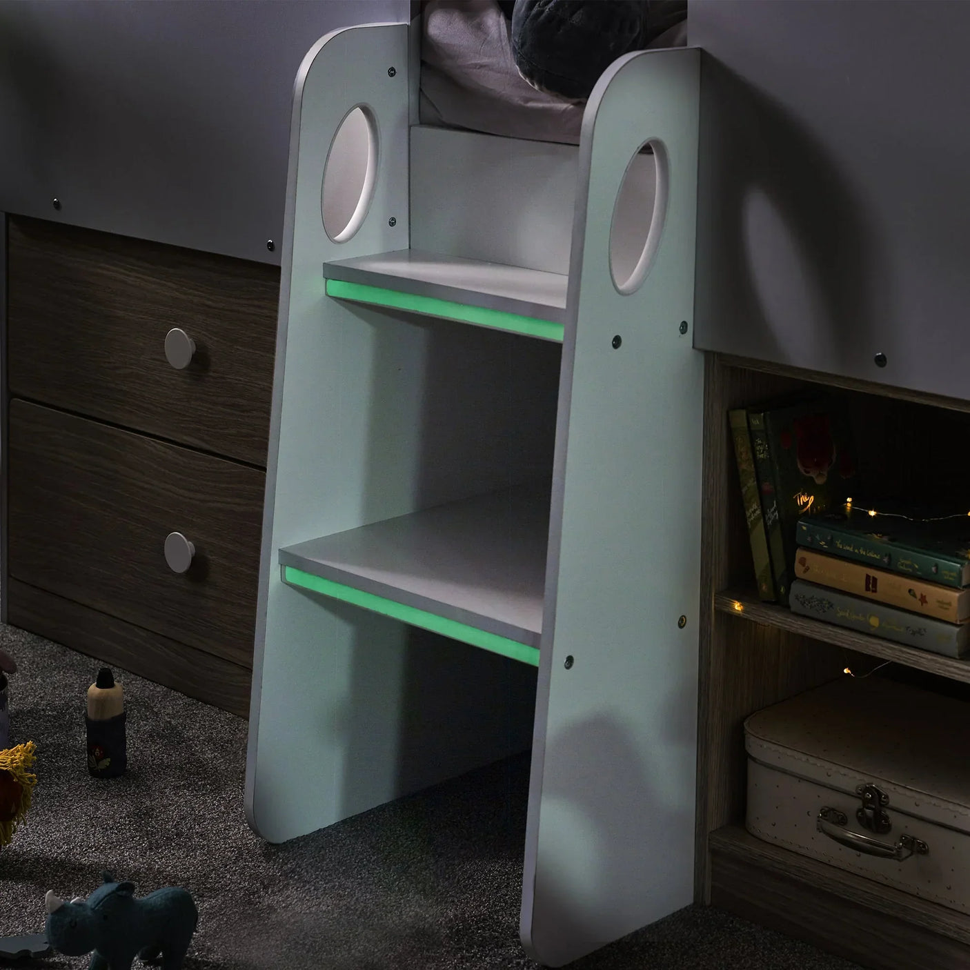 Orpheus midsleeper bed ladder with pale wood drawers, shelf storage, and books at night