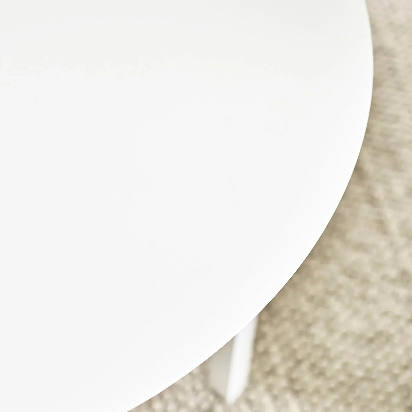 White round table edge on textured beige carpet