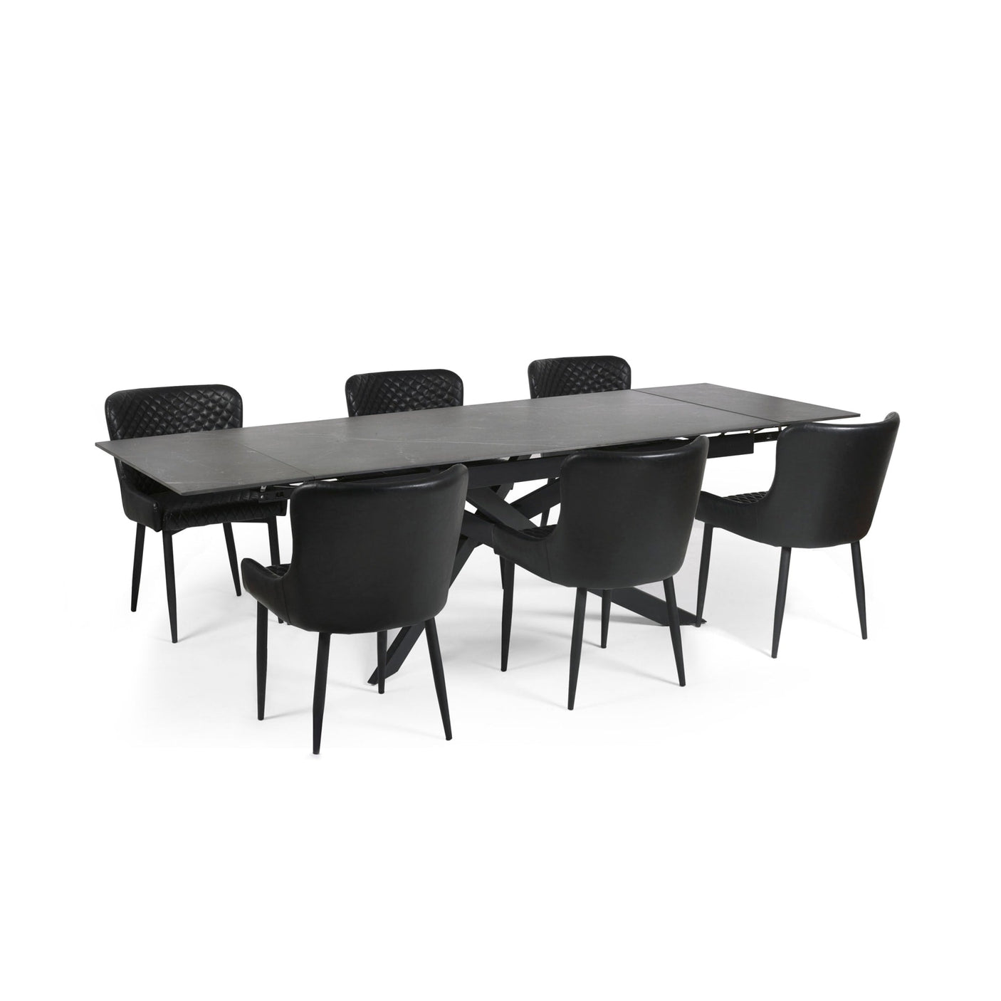 Extended black dining table with six black leather chairs with diamond quilted backrests on white background.
