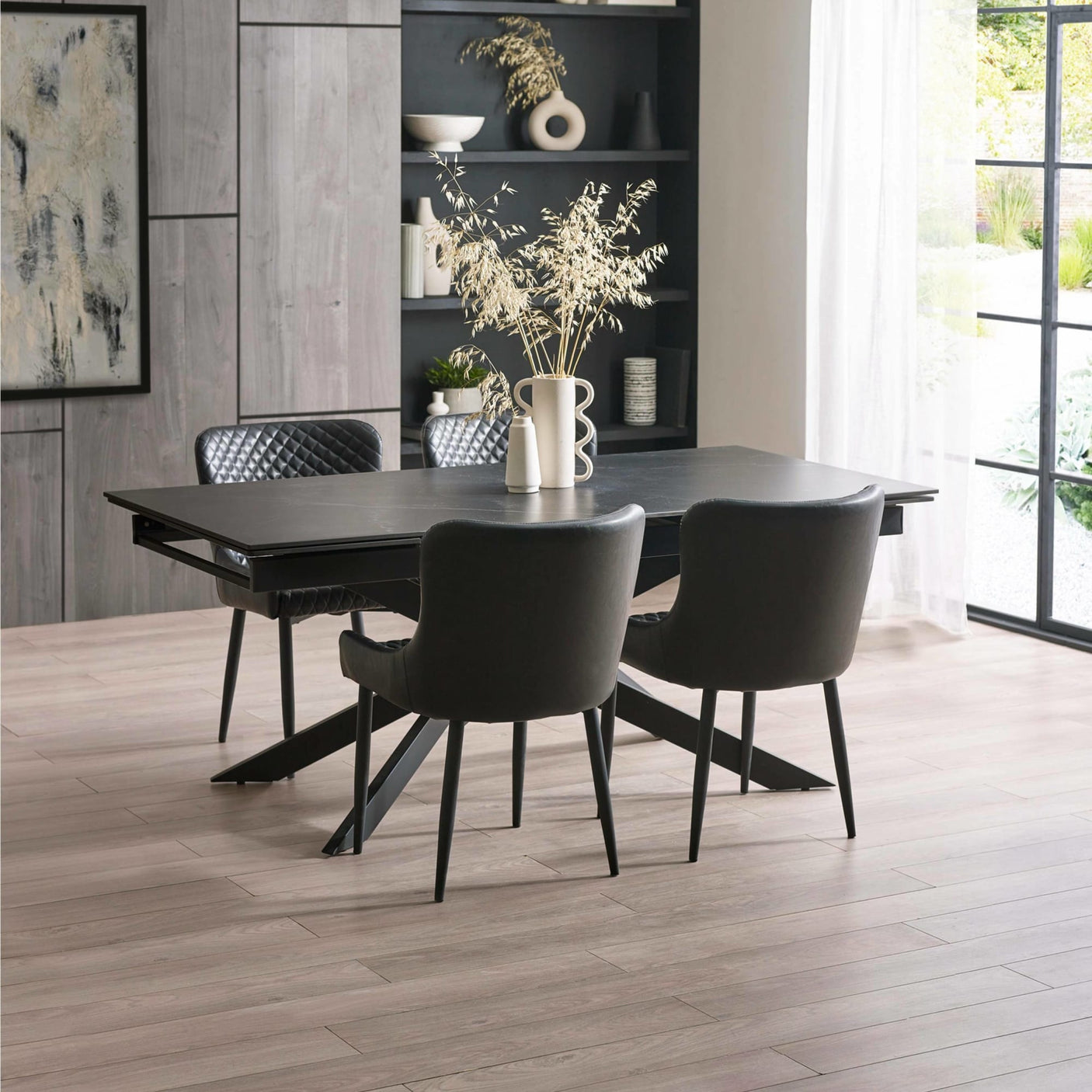 Black rectangular dining table with black leather chairs, light wood floor, modern room setting