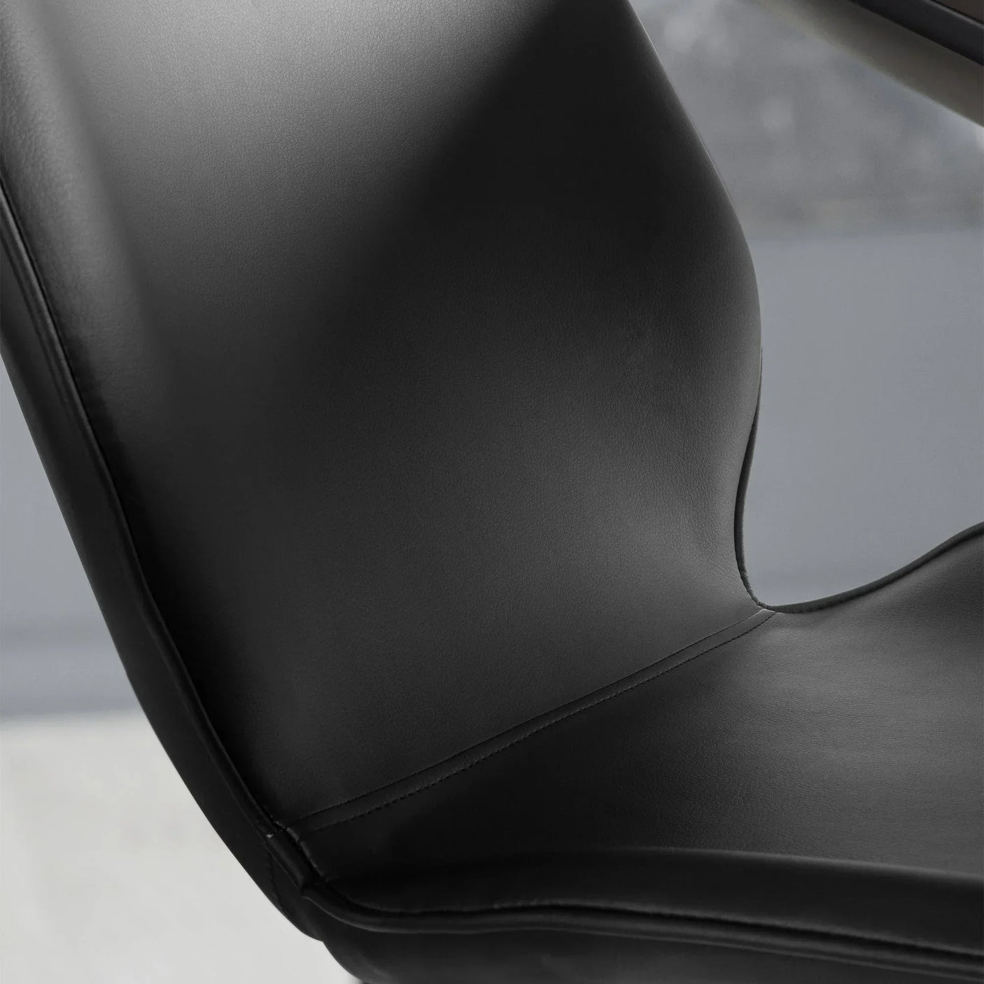 Close-up of black dining chair seat and curved backrest with smooth faux leather upholstery
