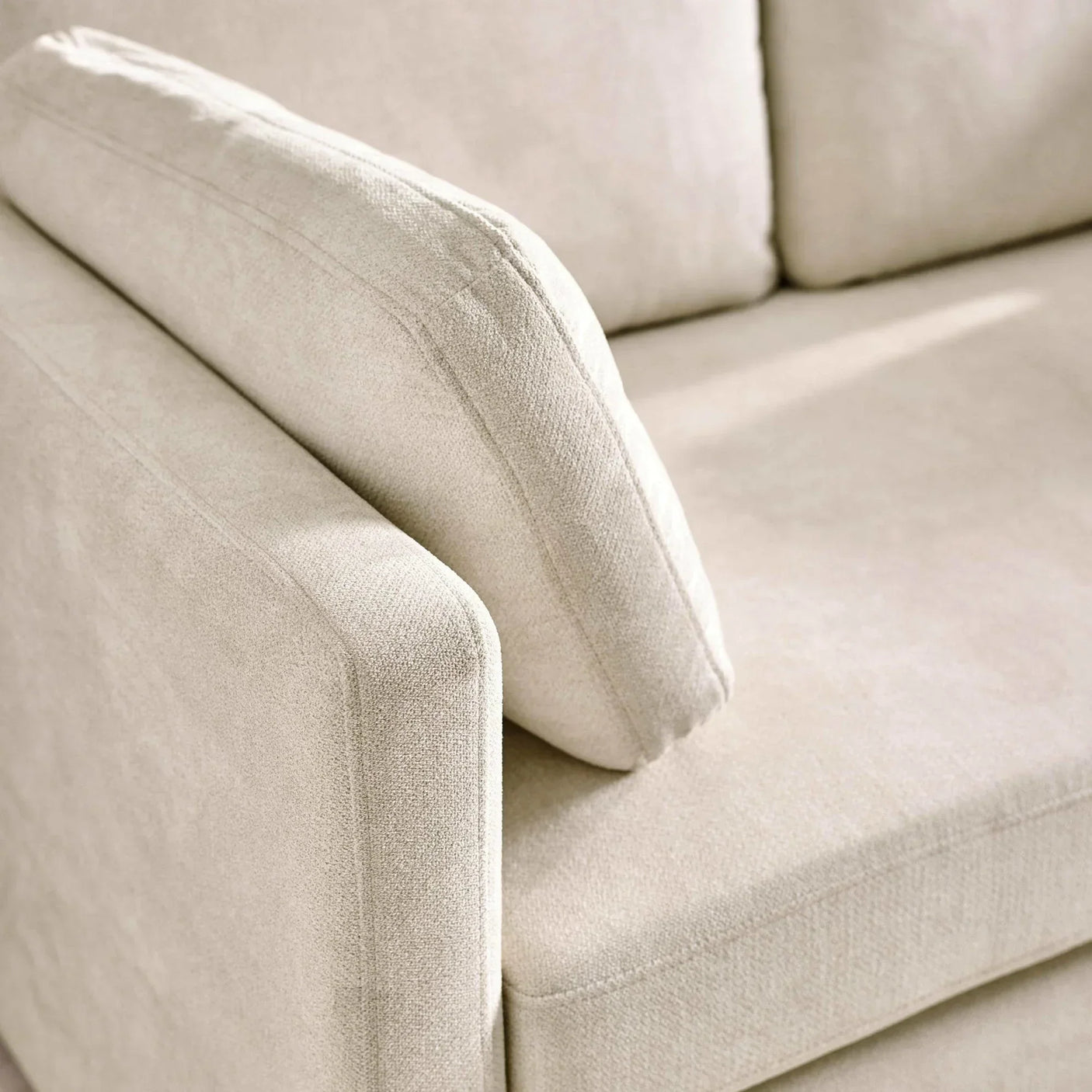 Beige fabric sofa armrest and cushion close up showing textured upholstery