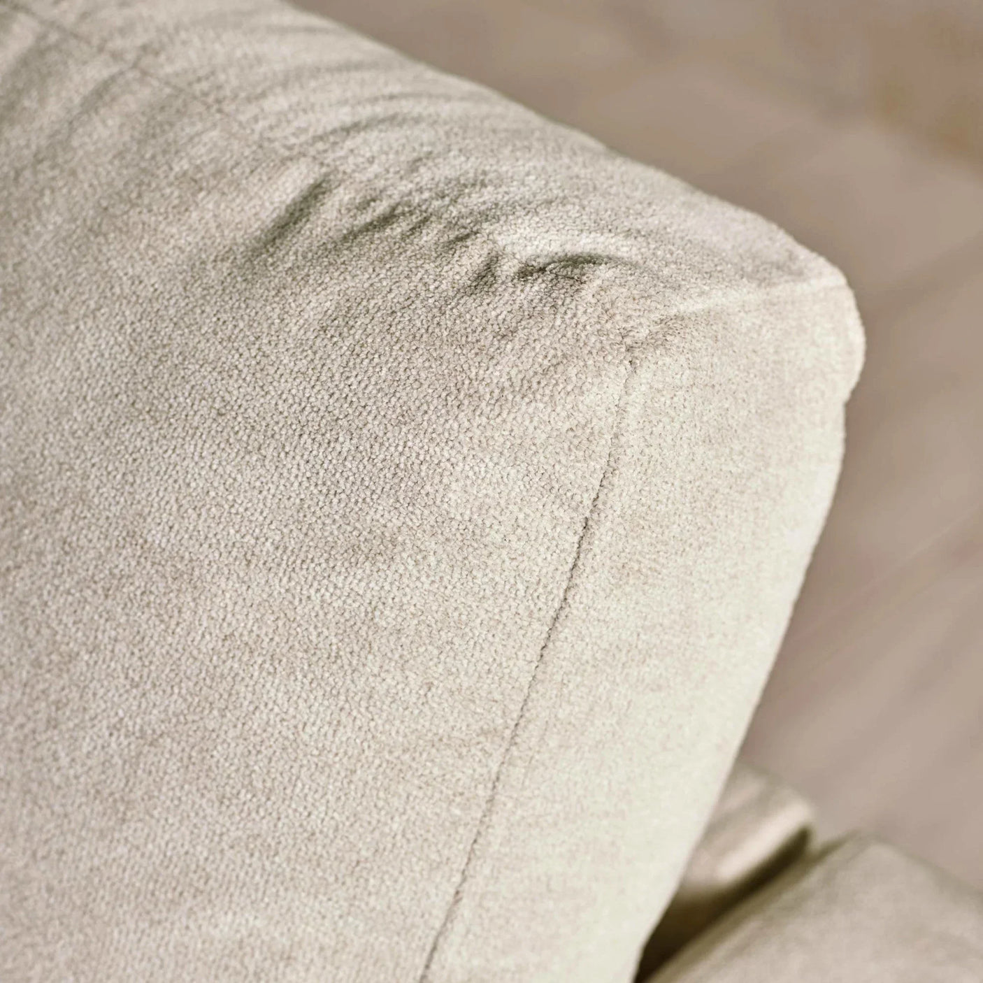 Closeup of beige fabric sofa armrest with textured upholstery