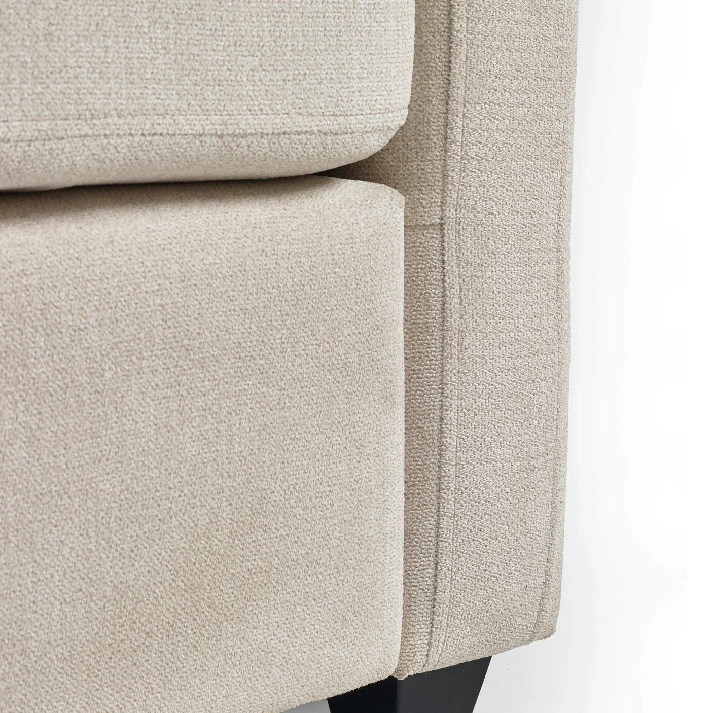 Close up of beige fabric sofa corner with textured upholstery and black leg
