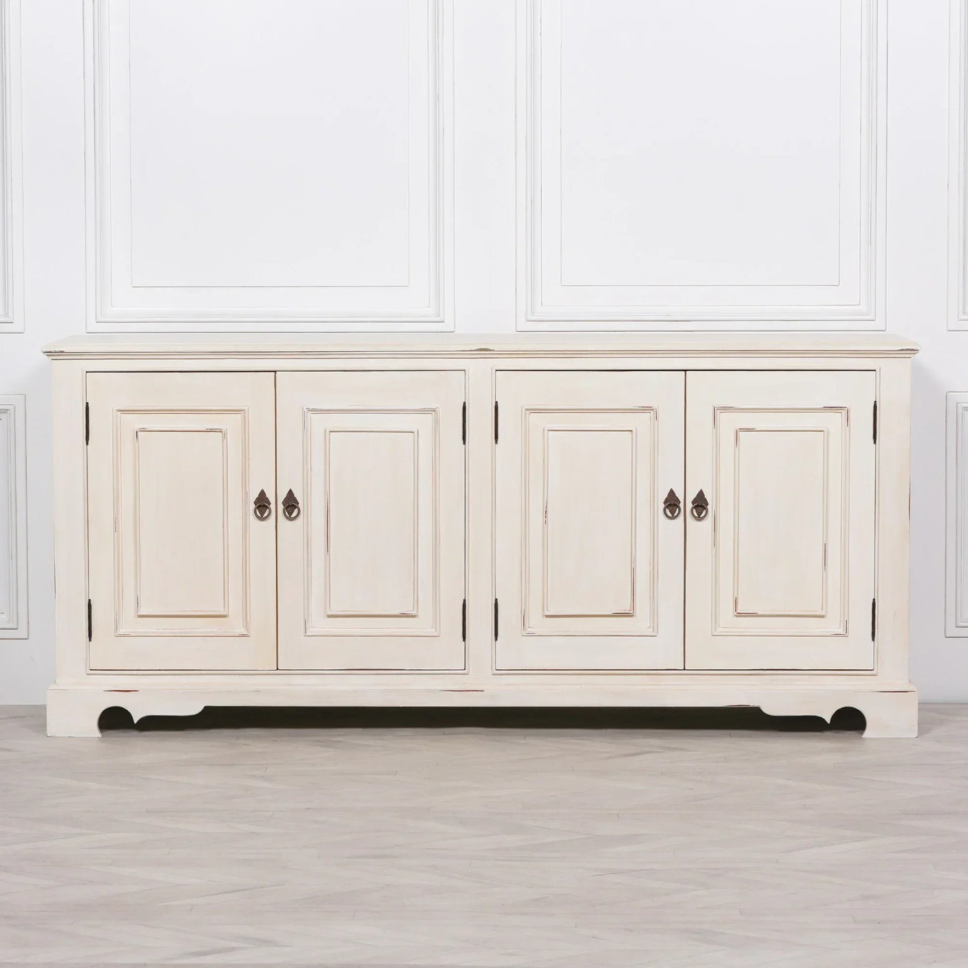 Cream painted wood sideboard with four paneled doors and metal handles on light floor