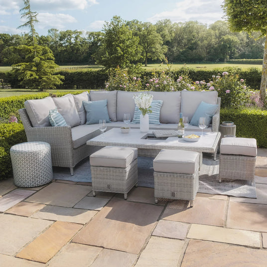 Grey rattan garden corner sofa set with cushions, stools, and table on patio