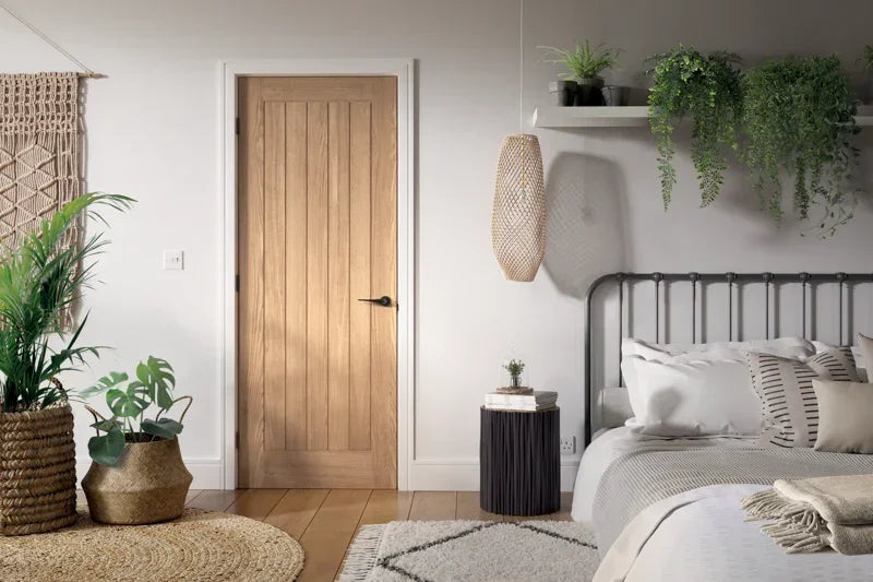 Oak internal door in modern bedroom with plants, natural rug and metal bed frame