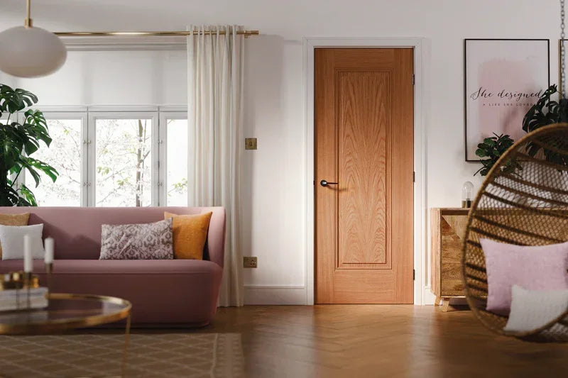 Oak interior door with panel design in modern living room with pink sofa and rattan chair