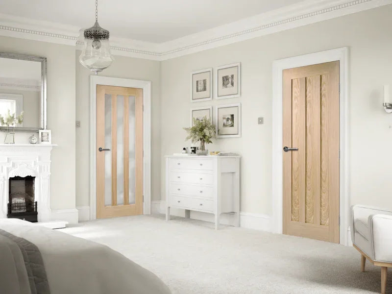 Oak pre-finished interior doors in a bright bedroom with white furniture and fireplace