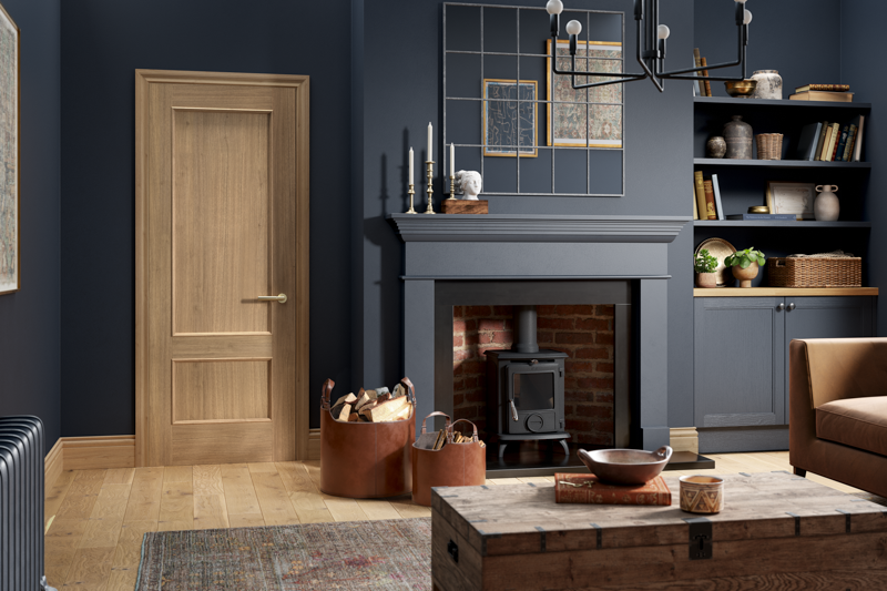 Oak interior door with wood flooring beside fireplace and navy fitted shelves in living room