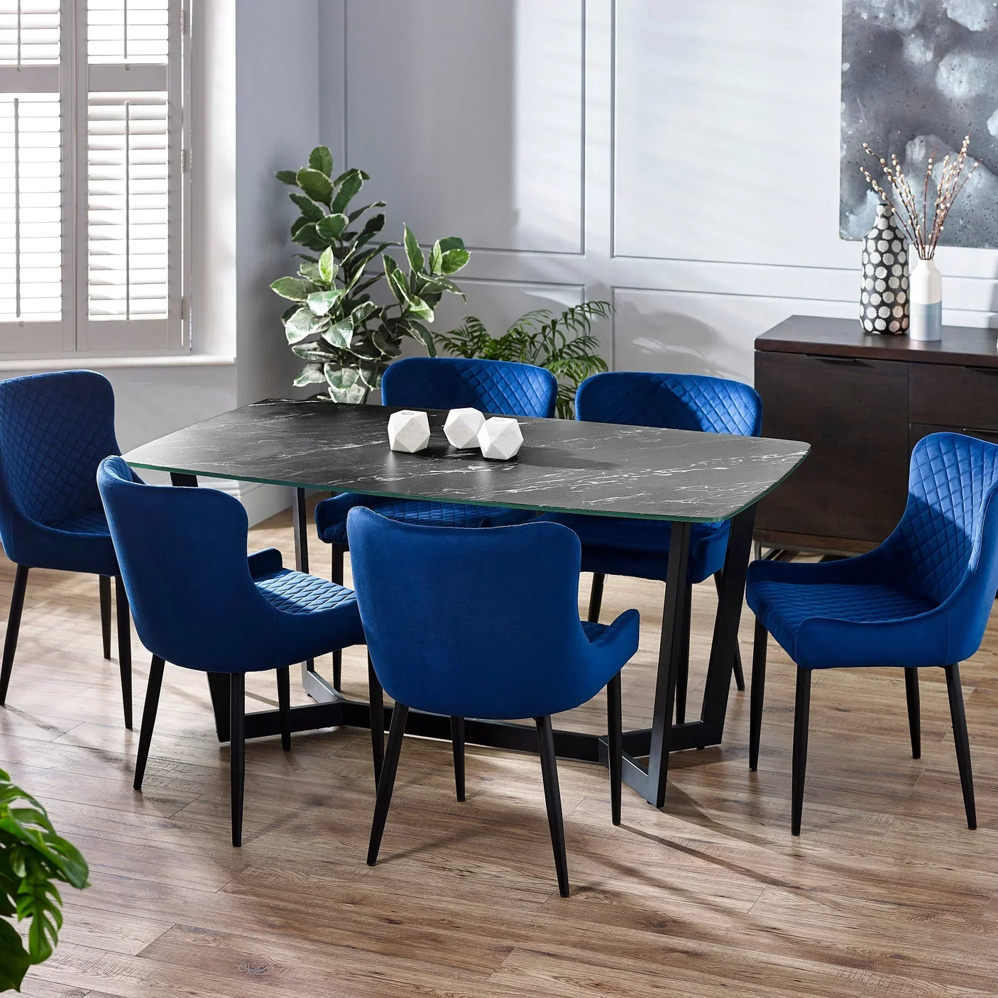 Black marble dining table with six luxe blue chairs in modern dining room set