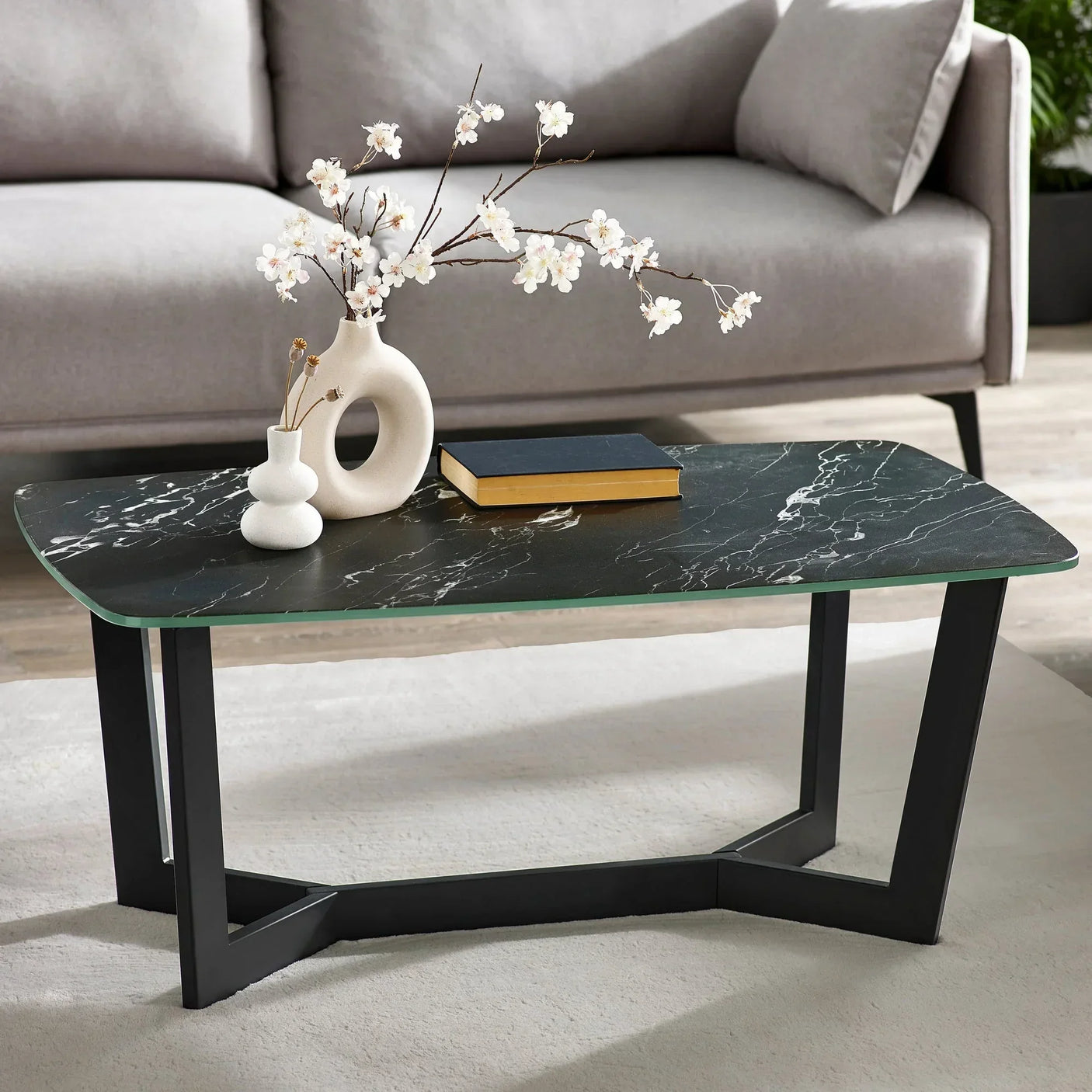 Black marble coffee table with modern metal legs, decorative vases and book in living room
