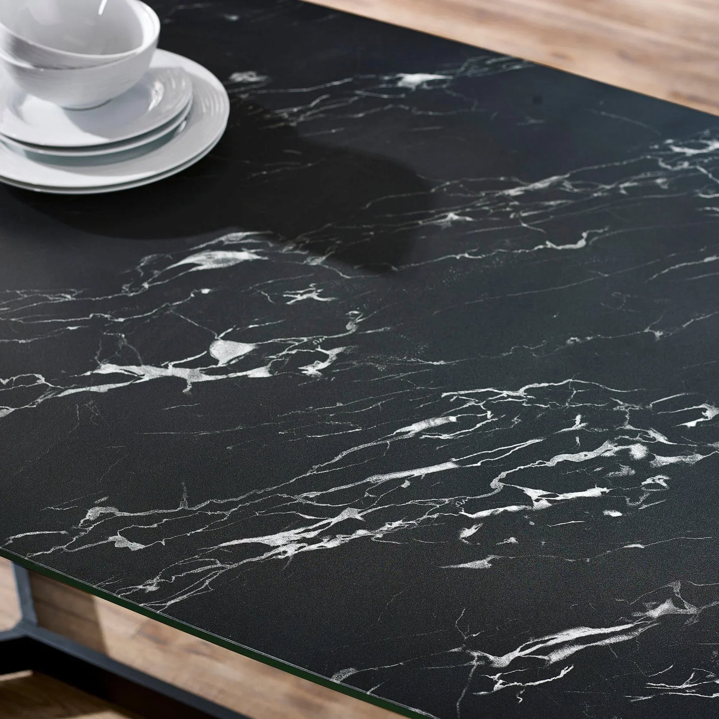 Black marble dining table top with white veining and stacked white plates