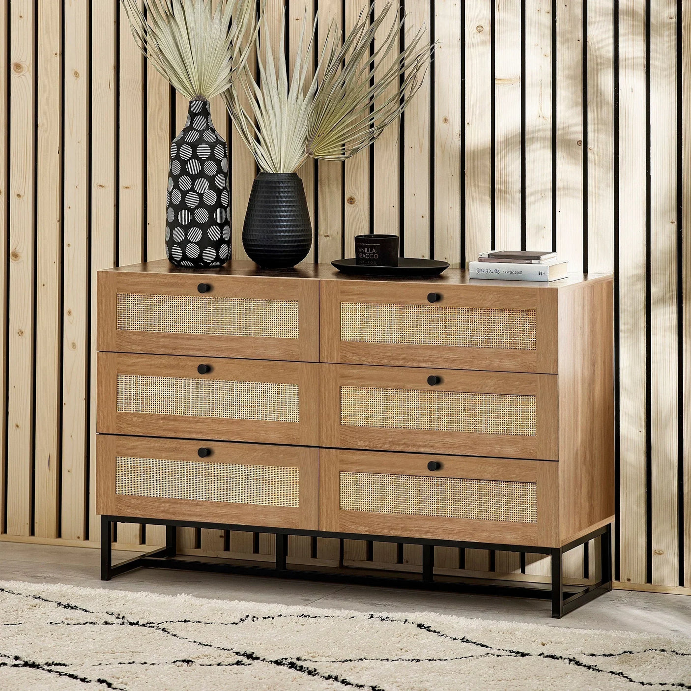 Oak 6 drawer chest with rattan fronts and black metal legs against wood panel wall
