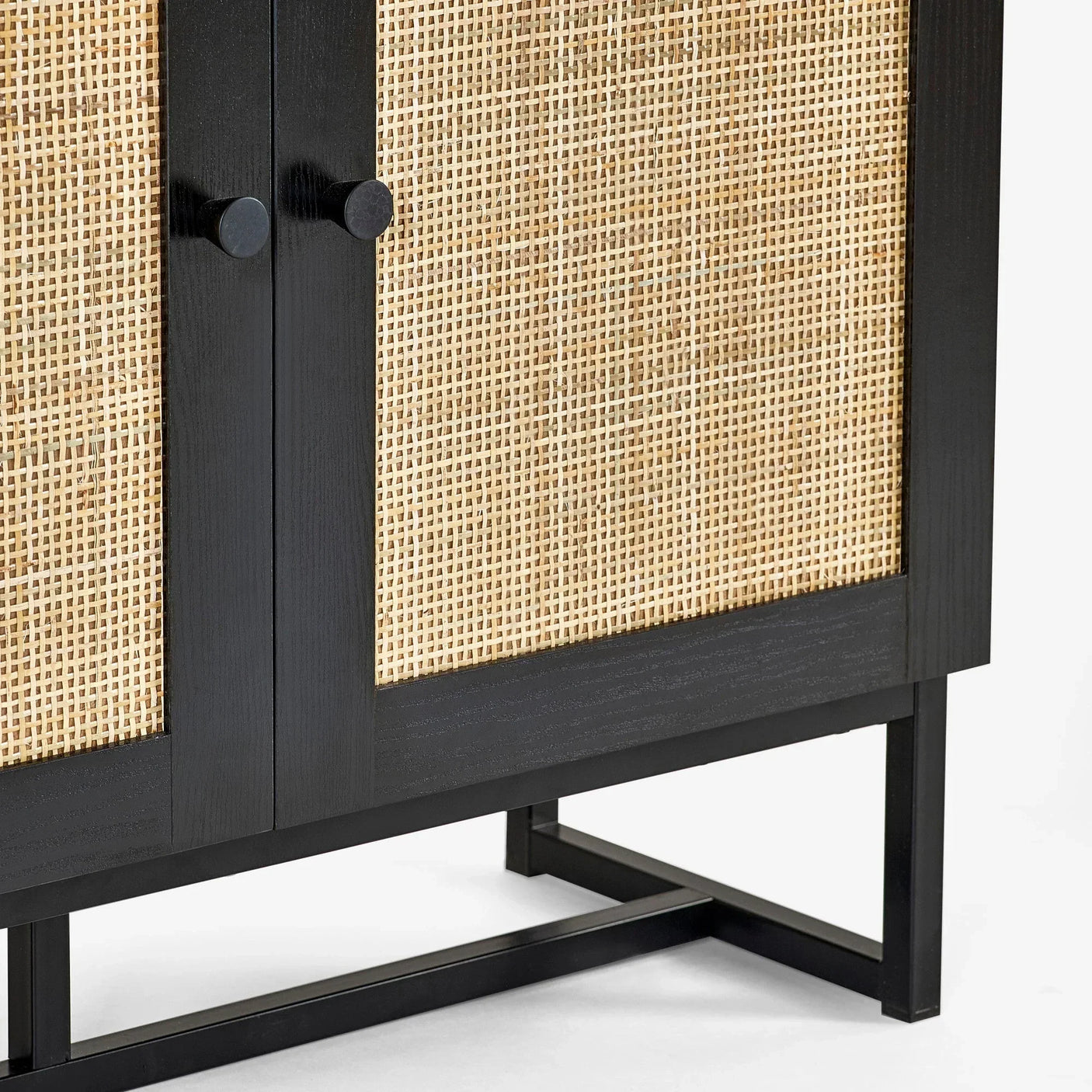 Closeup of black wood and natural rattan sideboard with metal frame and double doors