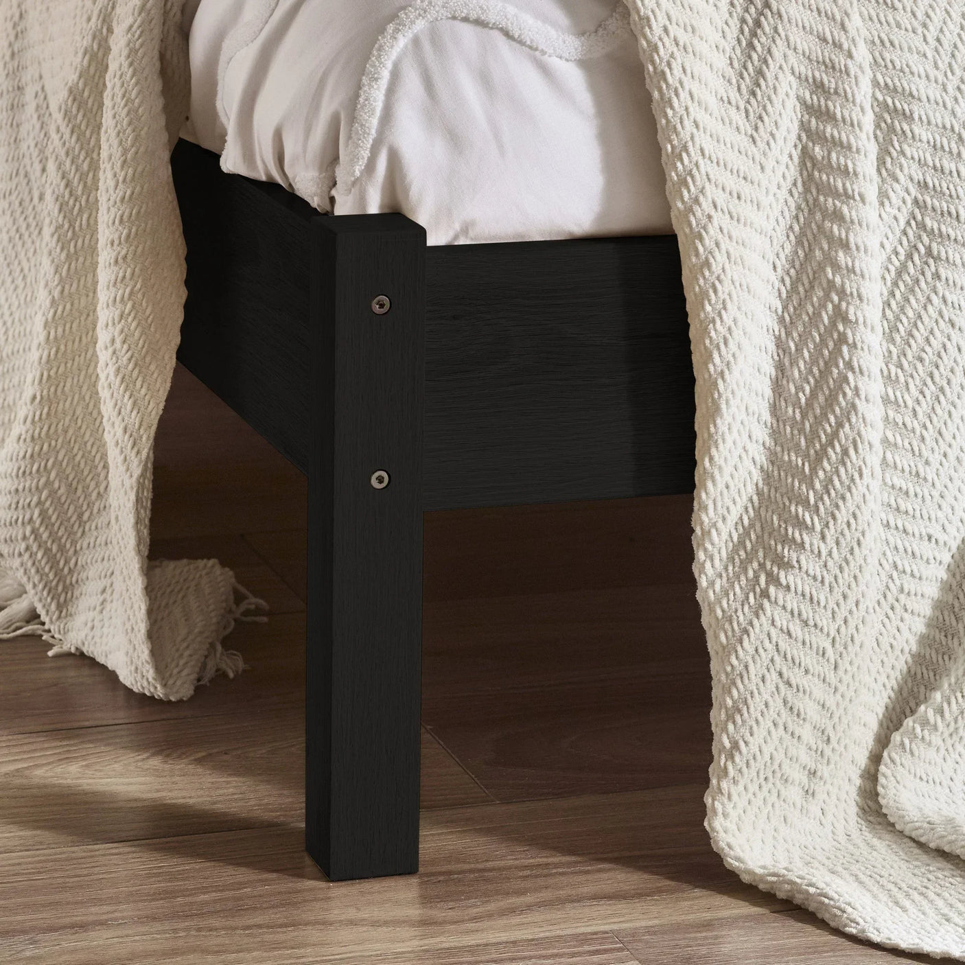 Padstow black rattan double bed frame leg and side detail on wooden floor