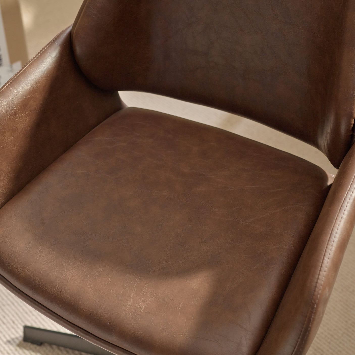 Close-up of padded brown faux leather seat of swivel office chair on carpet
